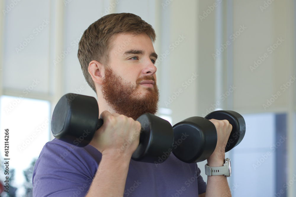 Young happy athletic man is training in the gym doing exercise with barbell
