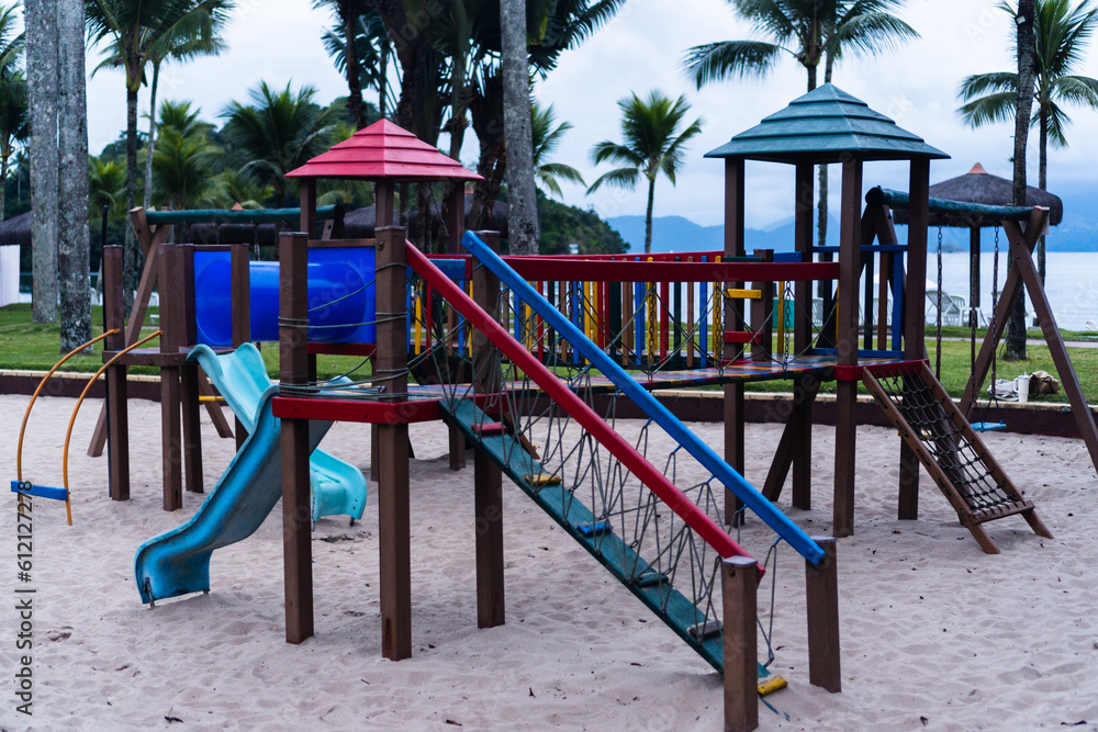 Outdoor playground with toy for children. Coconut trees and the beach in the background. Lush nature environment. Slide, tunnels among others. Cloudy day Outdoor playground with toy for children. Coconut trees and the beach in the background. Lush nature environment. Slide, tunnels among others. Cloudy day