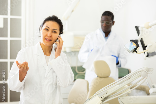 Portrait of friendly female dentist with a mobile phone. Invites the patient to undergo treatment