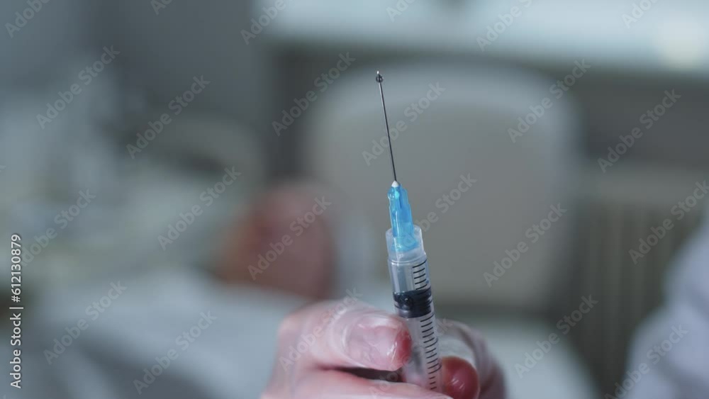 A doctor squeezes out excess air from the syringe A doctor squeezes out excess air from the syringe