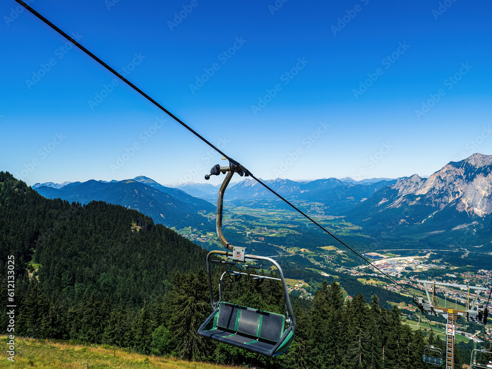 Chairlift ski lift chair going upwards no people empty in Austria, Carinthia, during summer with mountains in the background, clear sky, copy space
