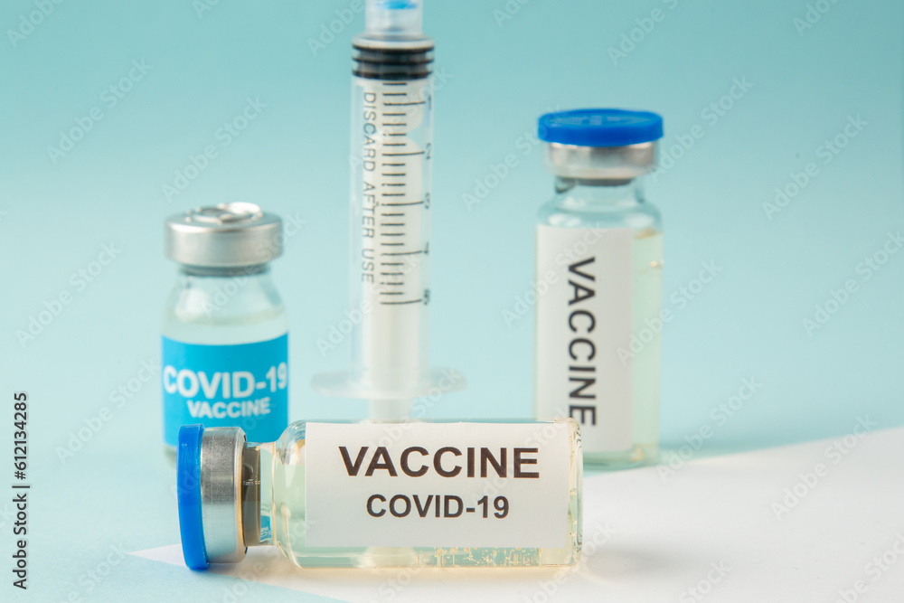 Close up view of COVID- vaccines in medical ampoules and disposable syringe on pastel blue and white background Close up view of COVID- vaccines in medical ampoules and disposable syringe on pastel blue and white background