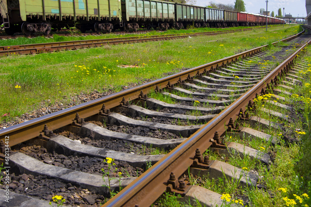 Railroad tracks with rails and sleepers against the backdrop of freight train cars. Railroad tracks with rails and sleepers against the backdrop of freight train cars.