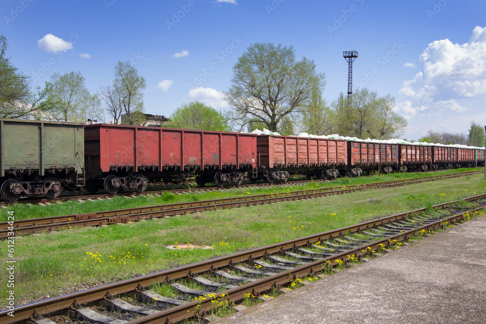 Railroad tracks with rails and sleepers against the backdrop of freight train cars. Railroad tracks with rails and sleepers against the backdrop of freight train cars.