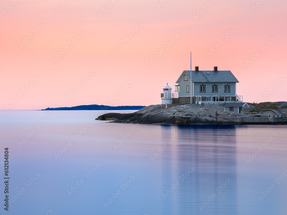 House and lighthouse on peninsula of a swedish coast in evening sunset light - long exposure