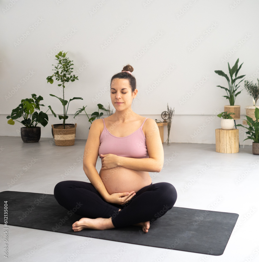 Pregnant woman practicing yoga in a yoga studio. Pregnant woman practicing yoga in a yoga studio.