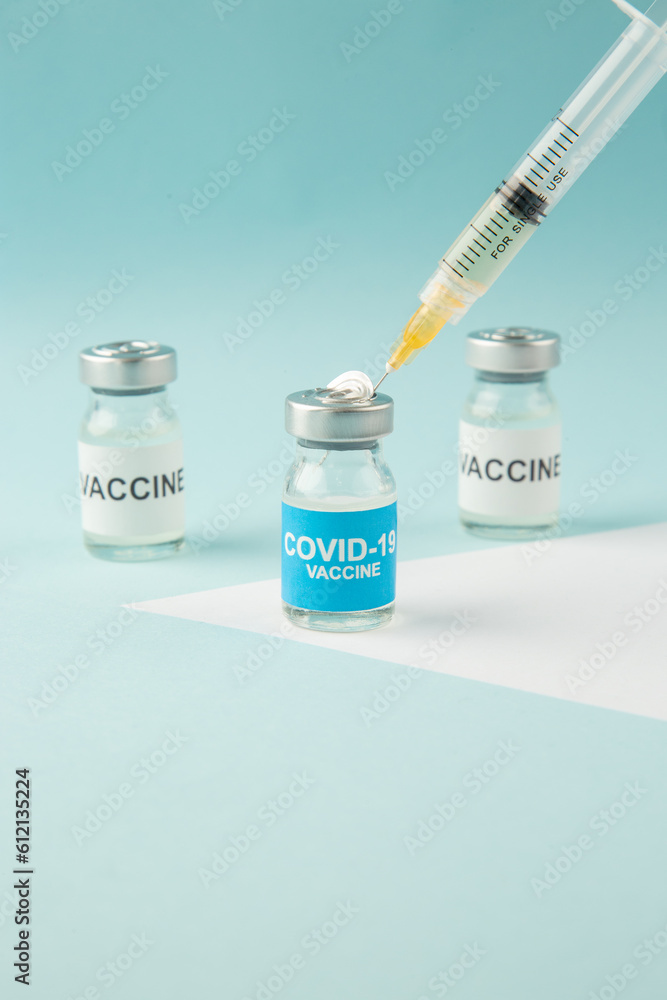 Close up view of hand vaccine ampoules and syringe on pastel blue and white background with free space Close up view of hand vaccine ampoules and syringe on pastel blue and white background with free space