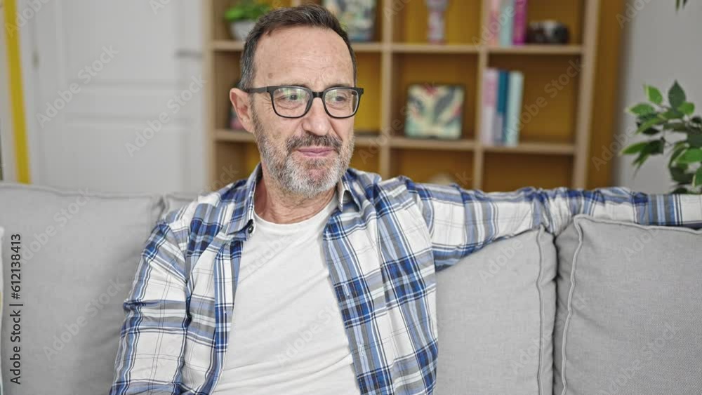 Middle age man smiling confident sitting on sofa speaking at home Middle age man smiling confident sitting on sofa speaking at home