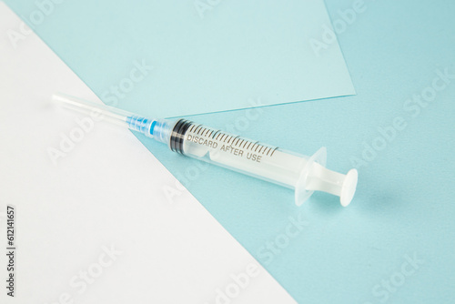 Front close view of disposable syringe on blue white background with free space