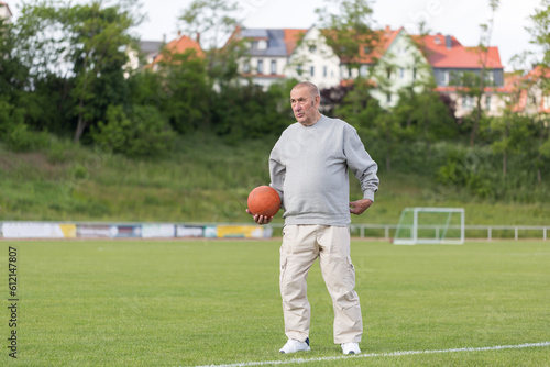 An elderly man goes in for sports on the background of the stadium on a summer evening 