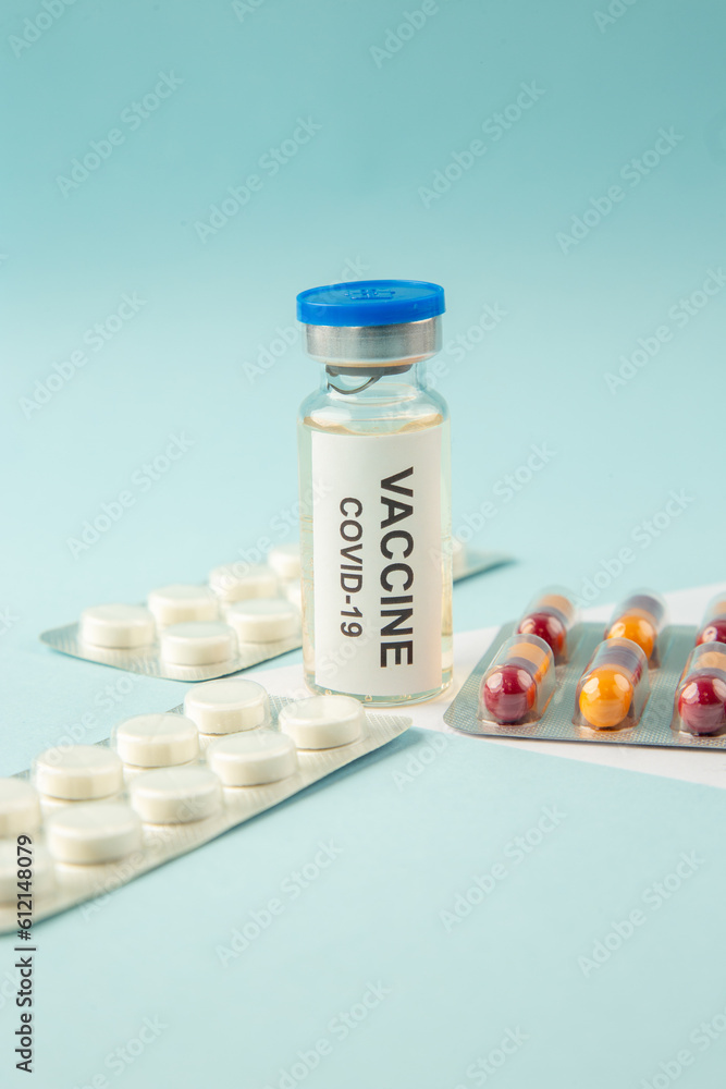 Front view of vaccine in medical ampoule packed pills capsules on pastel blue background Front view of vaccine in medical ampoule packed pills capsules on pastel blue background