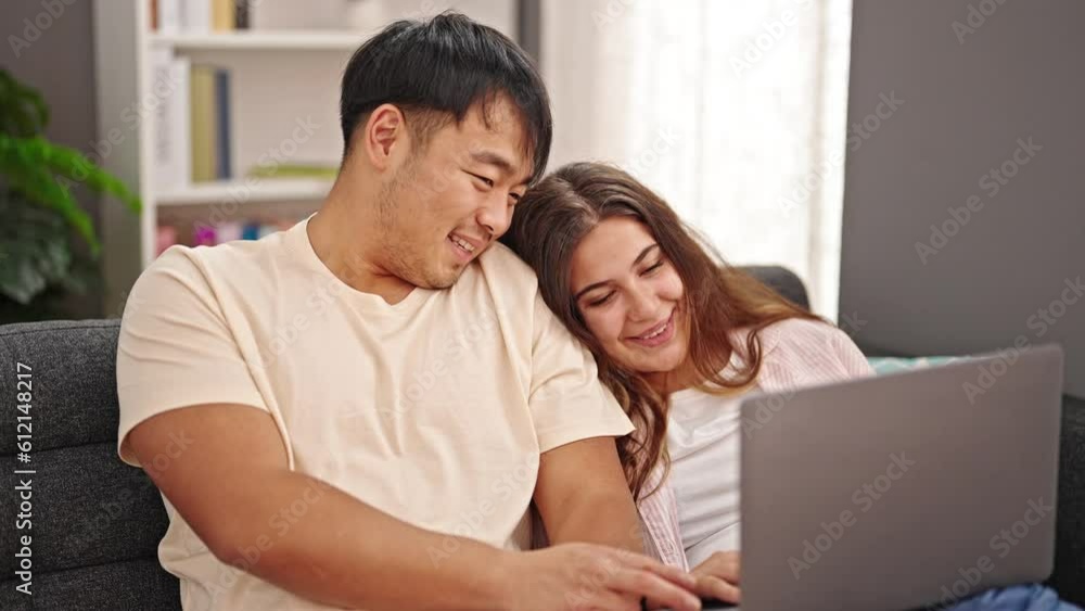 Man and woman couple sitting on sofa using laptop at home Man and woman couple sitting on sofa using laptop at home