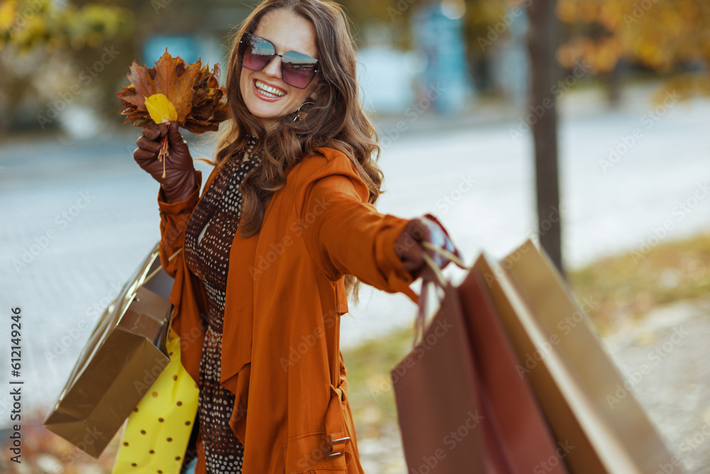 happy stylish woman in brown trench coat with shopping bags