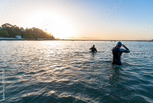 Wearing wetsuits, two men wade into the Aquatic Park Lagoon for an evening swim in the San Francisco Bay, California photo