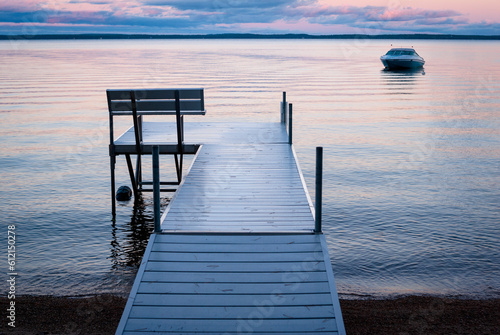 Colorful sunrise and an aluminum dock at Sebago Lake, Maine, with a boat in the distance photo