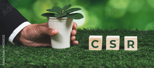 Businessman holding plant pot with cube symbolizing CSR. Ethical and eco-friendly green business with no CO2 emission policy. Committed to corporate social responsibility for greener community. Alter