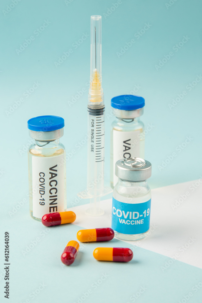 Side view of vaccines for treatment Covid- in medical ampoules capsules and syringe on white blue background Side view of vaccines for treatment Covid- in medical ampoules capsules and syringe on white blue background