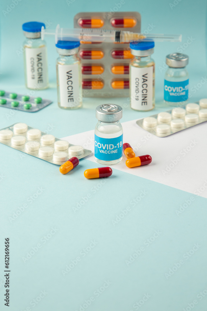 Top view of covid- vaccine in medical ampoules packed pills capsules on blue background Top view of covid- vaccine in medical ampoules packed pills capsules on blue background
