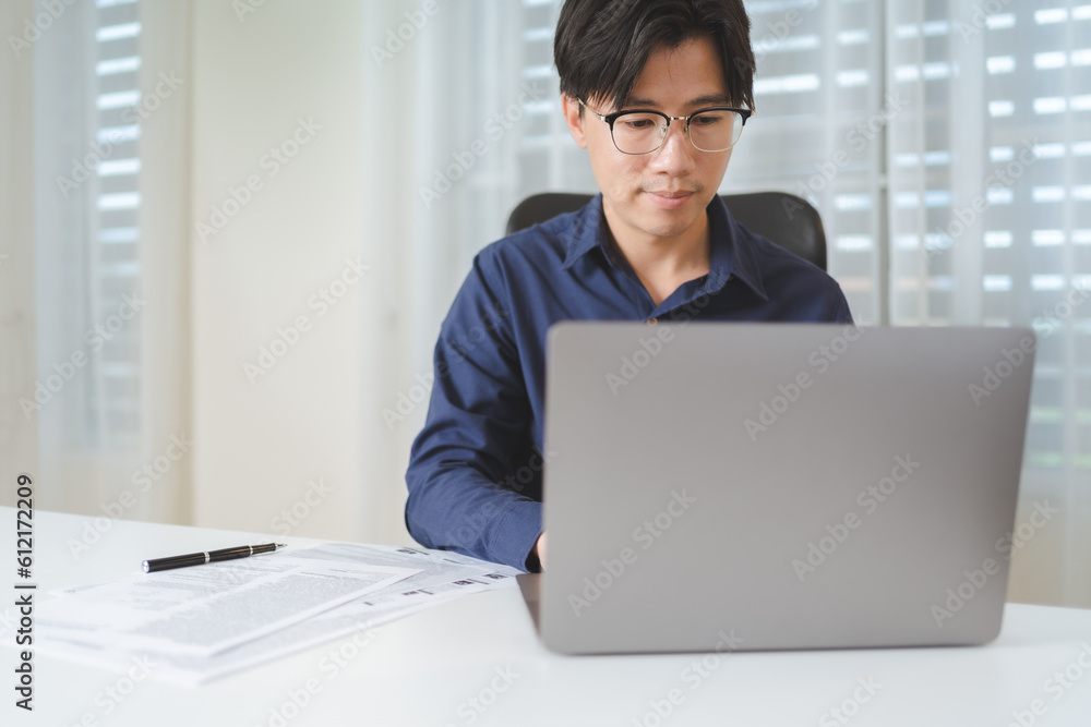 Happy Asian businessman, male businessperson using computer laptop with paperwork on desk at office. Professional entrepreneur business man wear eyeglasses, sitting to working, planning on workplace. Happy Asian businessman, male businessperson using computer laptop with paperwork on desk at office. Professional entrepreneur business man wear eyeglasses, sitting to working, planning on workplace.