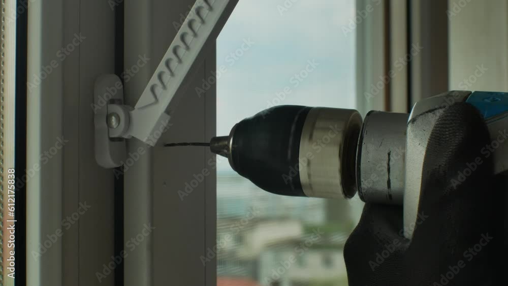 Vidéo Stock The master drills a hole with a drill in a plastic window