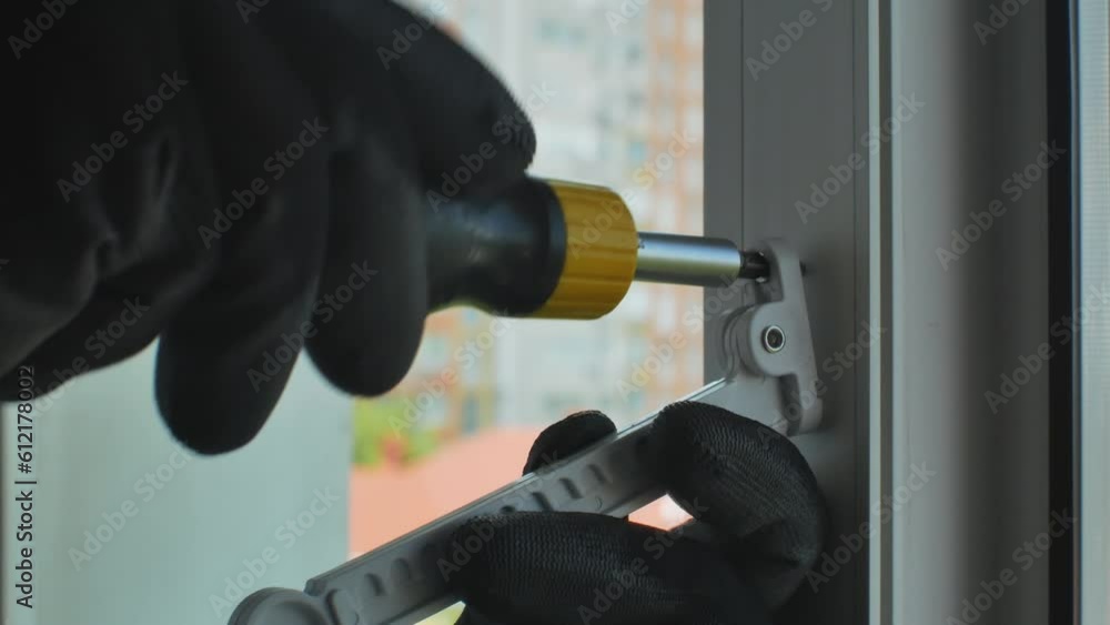 Close-up of a man's hand in a construction glove tightens a screw that ...