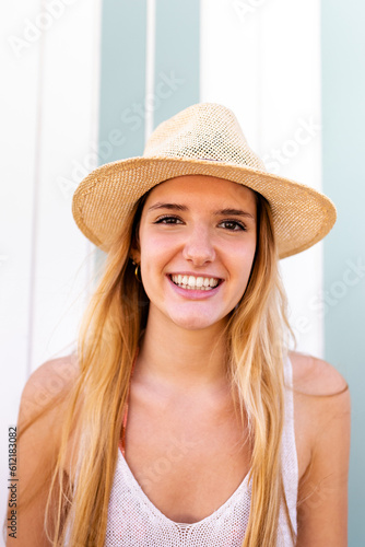 Headshot of young happy blond woman on vacation wearing hat looking at camera.