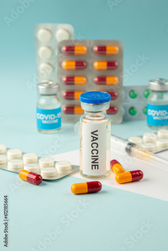 Vertical view of vaccine in medical ampoules packed pills and capsules for Covid- on blue background