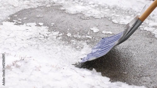 Removing ice with a beat up shovel from a sidewalk in winter at a very slow pace