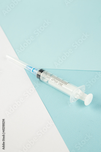 Vertical view of disposable syringe on blue white background with free space