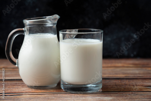 Fresh milk in a mug and jug on wooden table