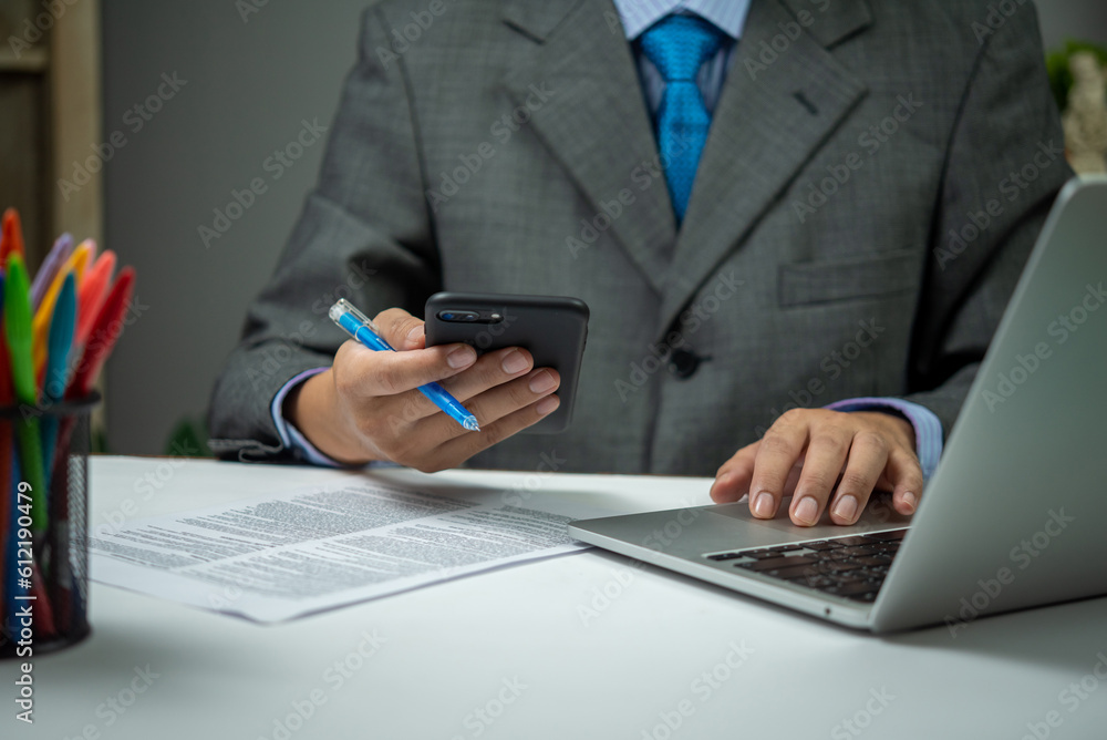 man using smartphone mobile application and document information with laptop on desk. man using smartphone mobile application and document information with laptop on desk.