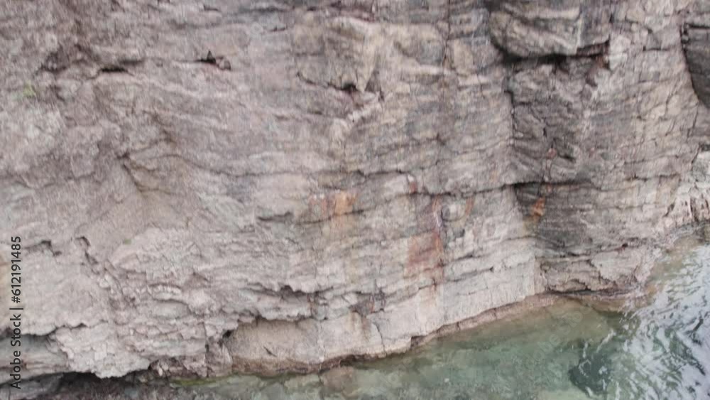 Rocky cliff reveals a stone beach, 4k, slow-mo drone shot Rocky cliff reveals a stone beach, 4k, slow-mo drone shot