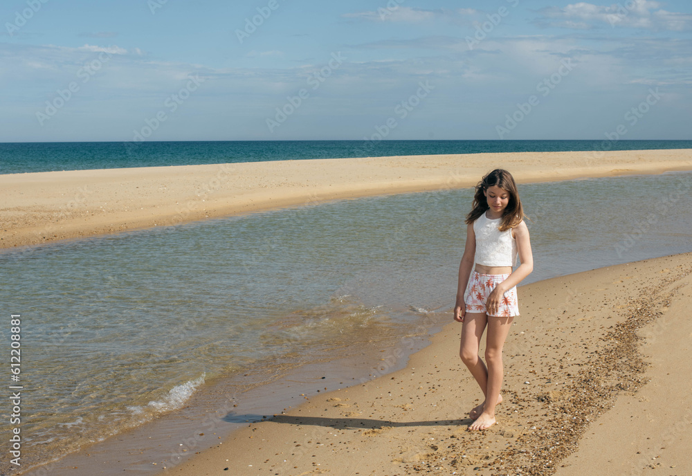 Beautiful fashionable young girl walking on the beach barefoot Beautiful fashionable young girl walking on the beach barefoot