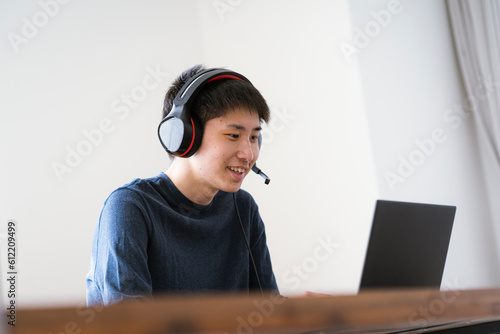 インカムを着けてパソコンを見る若い日本人男性 photo