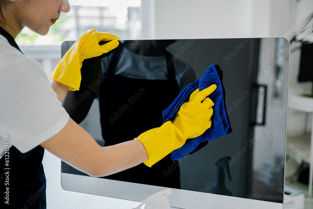Young woman using a computer cleaning cloth to disinfect the office.office cleaning staff cleaning maid Young woman using a computer cleaning cloth to disinfect the office.office cleaning staff cleaning maid