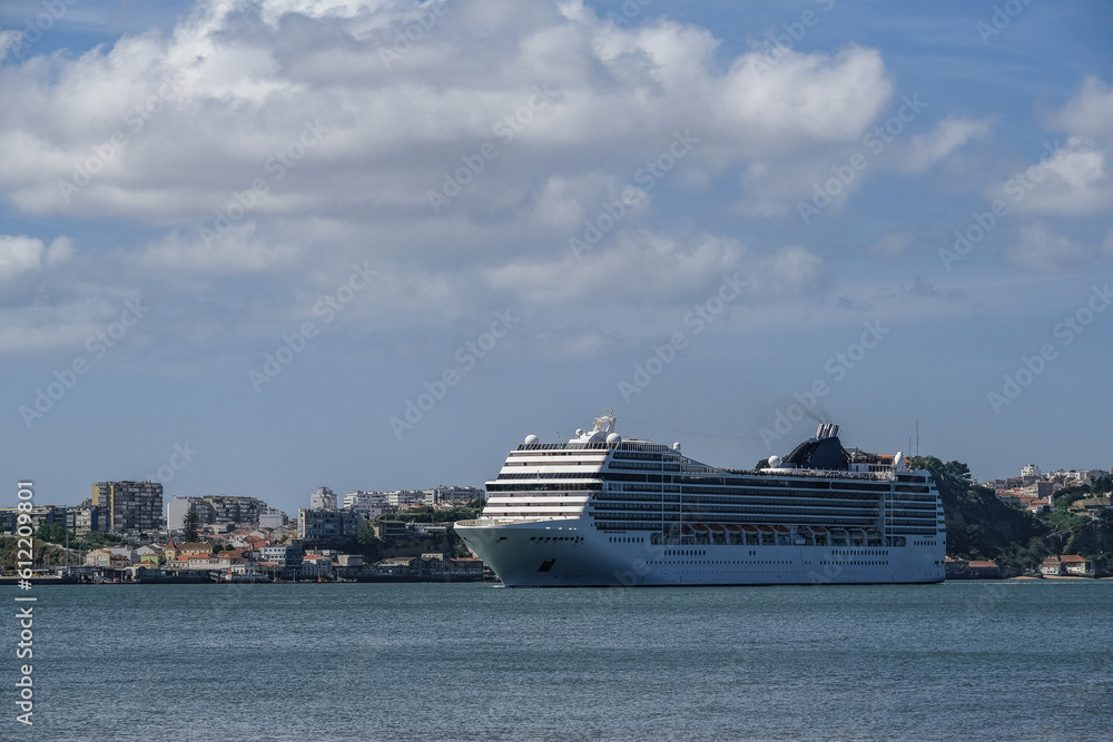Large modern liner cruiseship cruise ship Poesia, Orchestra, Magnifica or Musica in port of Lisbon, Portugal during Mediterranean cruising with city skyline, Christos statue and suspension bridge