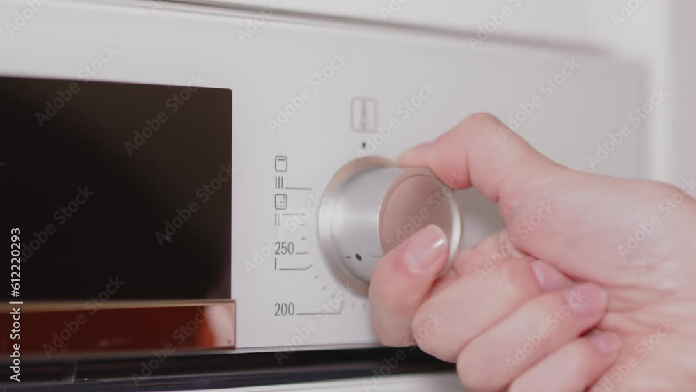 Woman's Hand Tuning On The Control Knob Of Electric Stove. - close up Woman's Hand Tuning On The Control Knob Of Electric Stove. - close up
