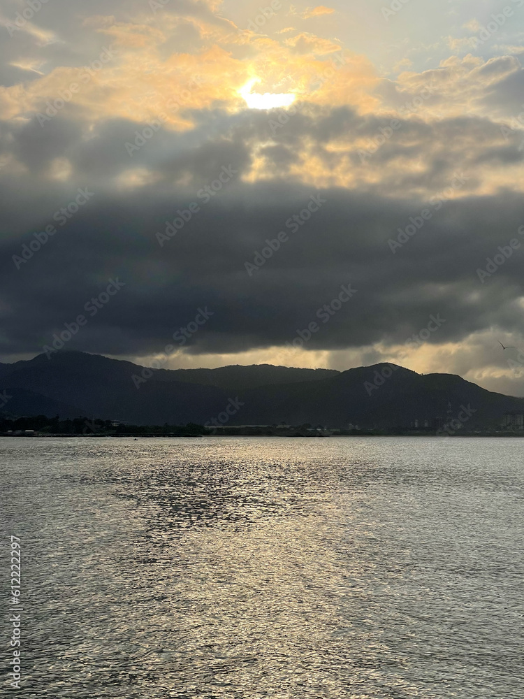 Sun reflected in the sea, very cloudy day. sunset, golden hour. in the background mountains. fog. seascape concept. selective focus Sun reflected in the sea, very cloudy day. sunset, golden hour. in the background mountains. fog. seascape concept. selective focus