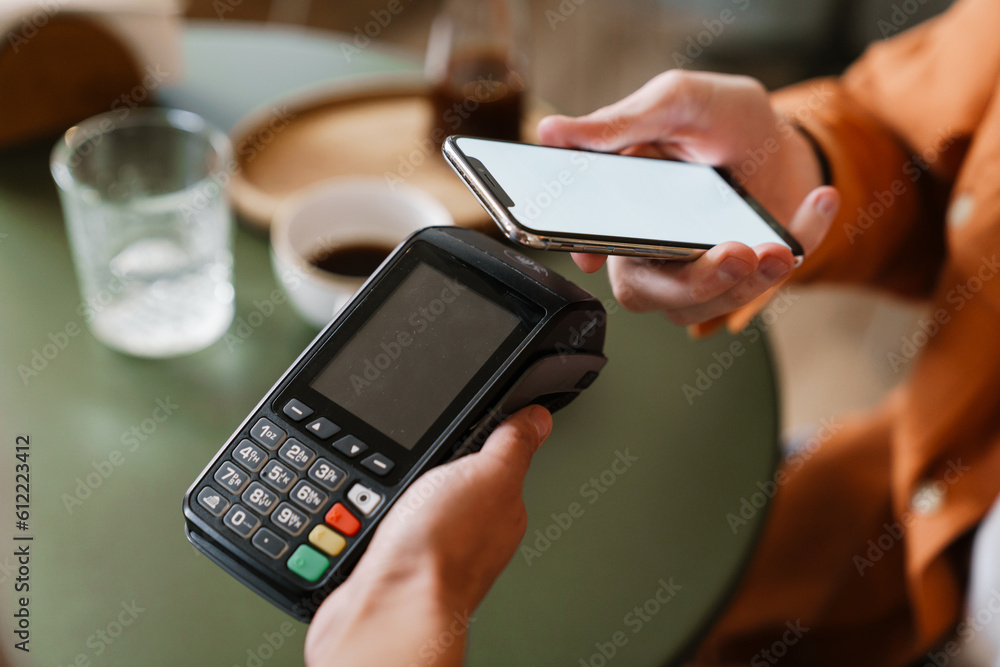 Close up man paying with mobile phone using contactless terminal