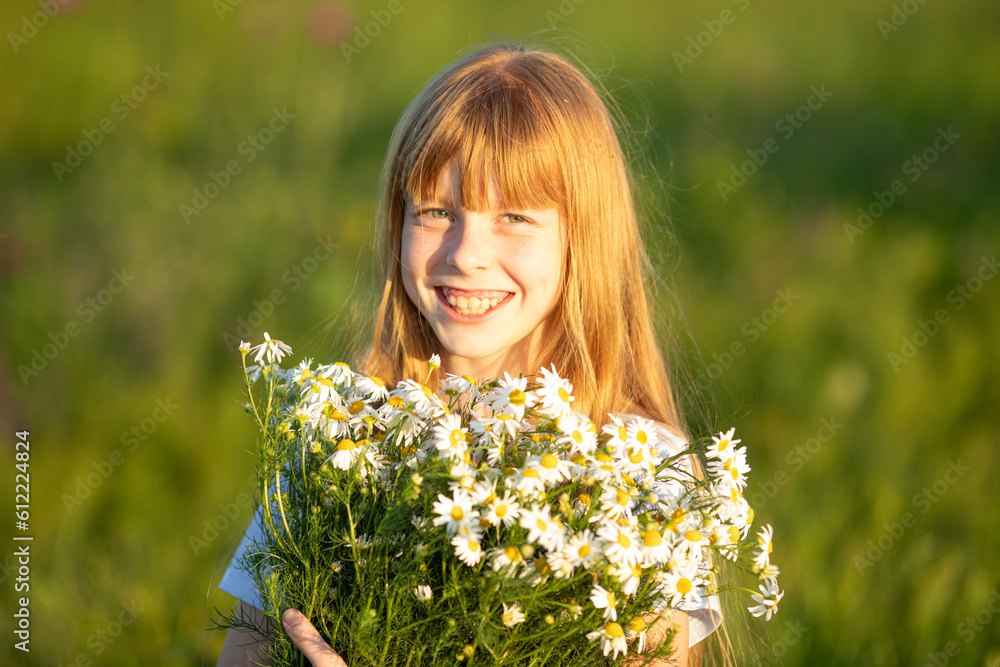 Portrait of a happy little laughing girl in a blue dress on a field with a bouquet of daisies on a sunny summer day at sunset. Summer concept Portrait of a happy little laughing girl in a blue dress on a field with a bouquet of daisies on a sunny summer day at sunset. Summer concept