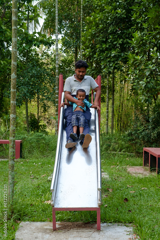 South asian young father playing in park slide with his little son , happy family moments 