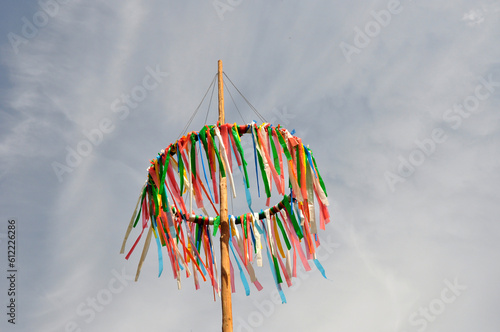 Maibaum oder Pfingstbaum: Hübscher Kranz mit bunten Bändern vor blauen Himmel mit Bewölkung im Mai