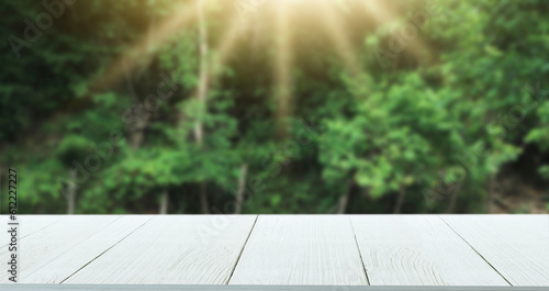 Wooden table top with natural green blurred background or various leaves, fresh bright sunlight, product empty concept.