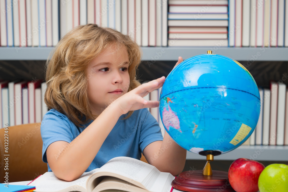 School kid pupil looking at globe in library at the elementary school. World globe. School child 7-8 years old with book go back to school. Little student. School kid pupil looking at globe in library at the elementary school. World globe. School child 7-8 years old with book go back to school. Little student.