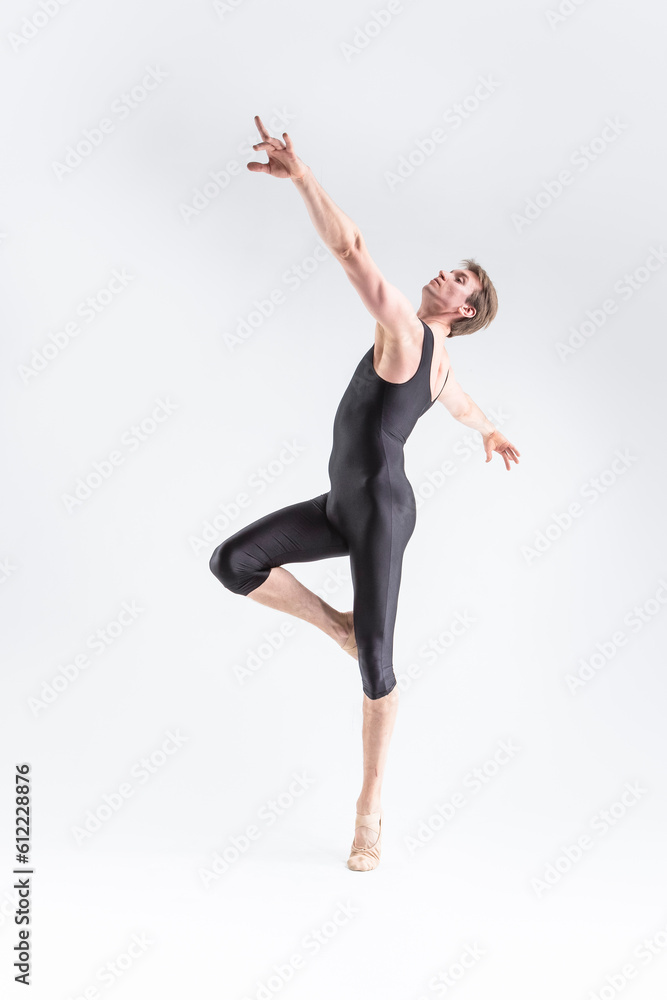 Modern Ballet Dancer Young Caucasian Athletic Man in Black Suit Posing Dancing in Studio On White With Lifted Hands.