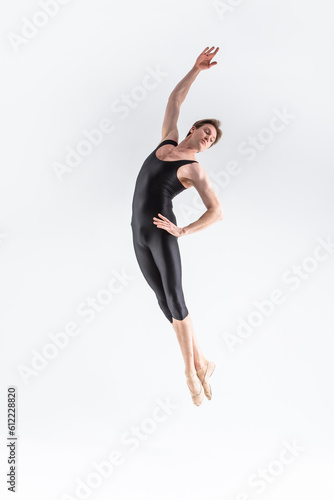 Modern Art Ballet of Young Caucasian Athletic Man in Black Suit Flying in Studio Over White Background With Lifted Hands.