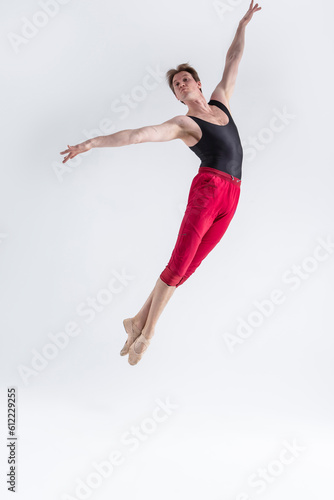 Fototapeta Naklejka Na Ścianę i Meble -  Flying Dancer. Contemporary Art Ballet With Young Flexible Athletic Man Posing in Flying Dance Pose in Studio on White