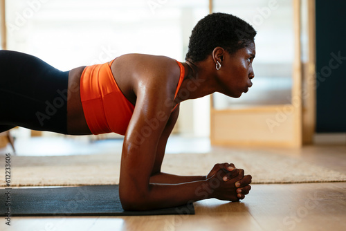 Active young woman practicing plank position at home