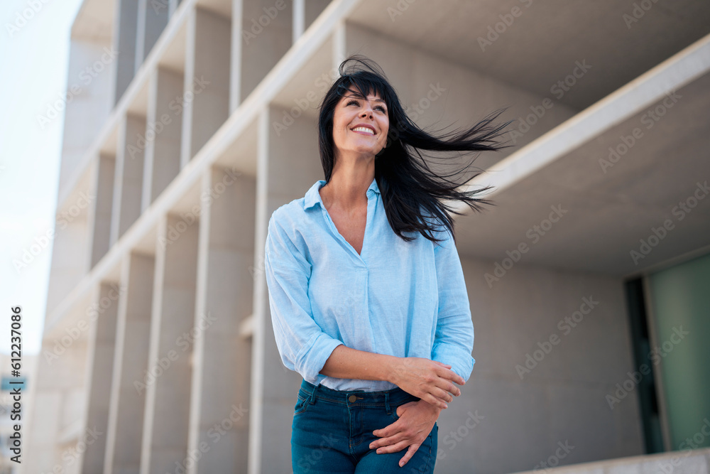 Smiling businesswoman with tousled hair in front of building Smiling businesswoman with tousled hair in front of building
