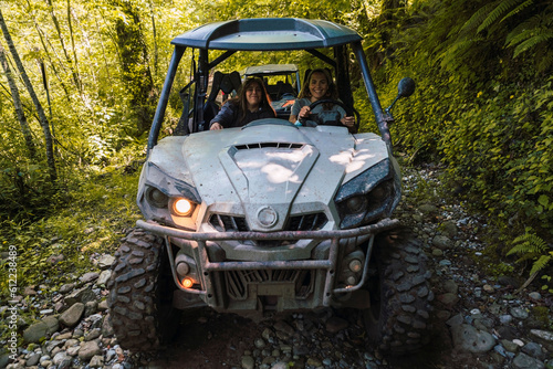 Young smiling friends riding buggy at forest photo